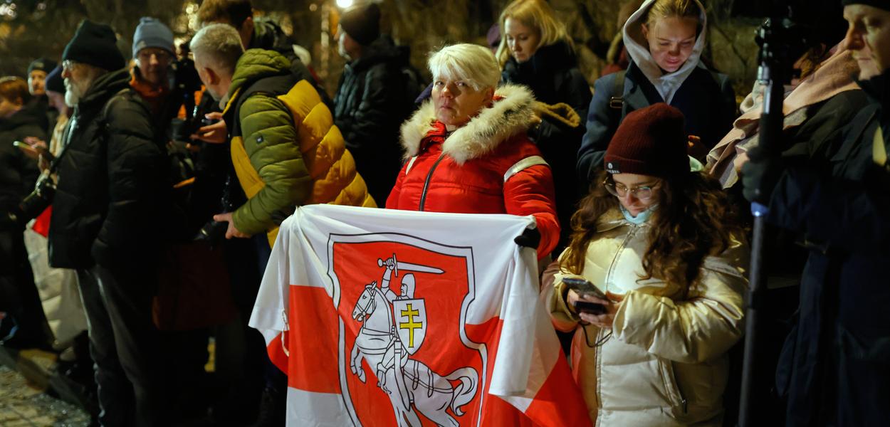 A woman holds an Old Belarusian flag as she waits at the U.S. Embassy for the release of Belarusian prisoners. (Photo: Mindaugas Kulbis)